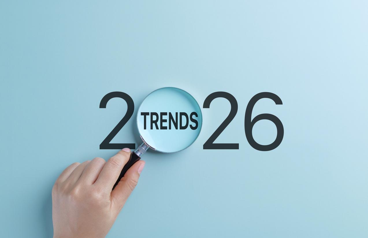 A hand holds magnifying glass focusing on the word Trends within the year 2026